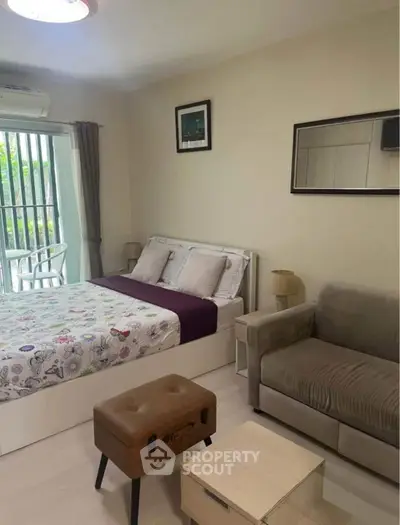 Cozy bedroom with modern decor, featuring a comfortable bed, stylish sofa, and natural light from large window.