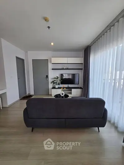 Modern living room with sleek furniture and large windows offering ample natural light.