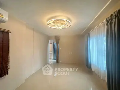 Spacious empty room with elegant chandelier and large windows, perfect for customization.