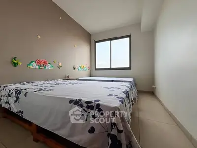 Spacious bedroom with two beds and large window for natural light.