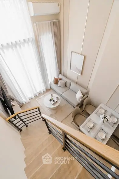 Modern duplex living room with elegant decor and dining area, featuring high ceilings and natural light.