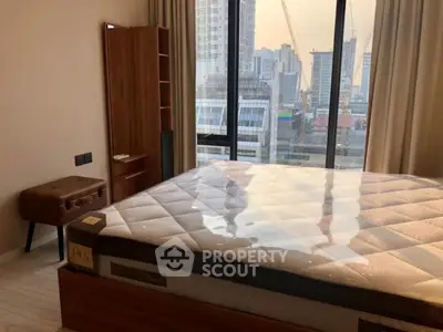 Modern bedroom with city view, featuring a large window and stylish furniture.