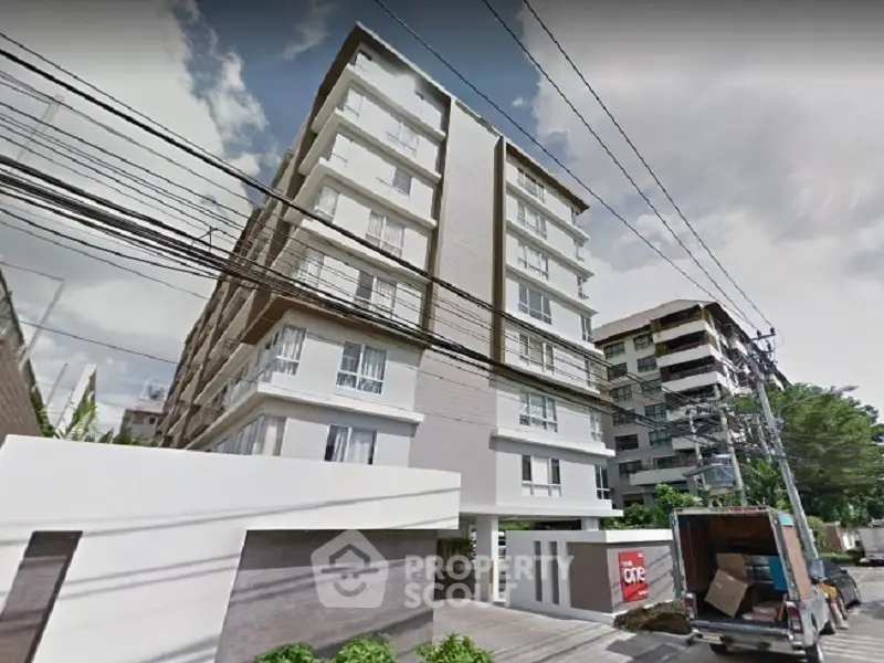 Modern apartment building exterior with lush greenery and clear blue sky.