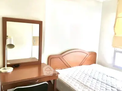 Cozy bedroom with wooden furniture and natural light, perfect for relaxation.