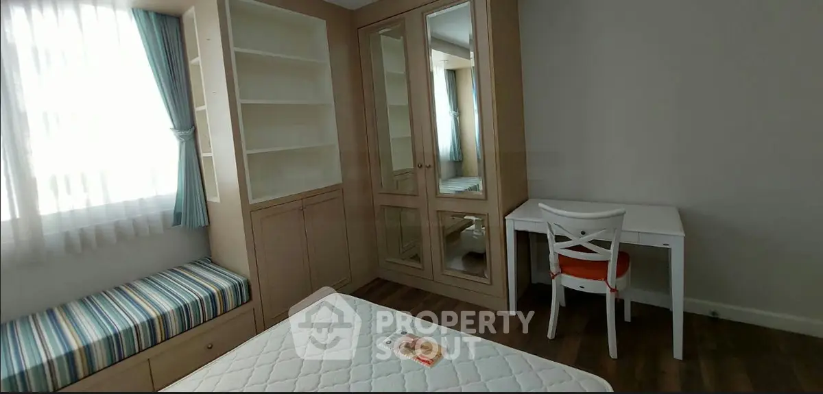 Cozy bedroom with built-in wardrobe, study desk, and window seat in modern apartment.