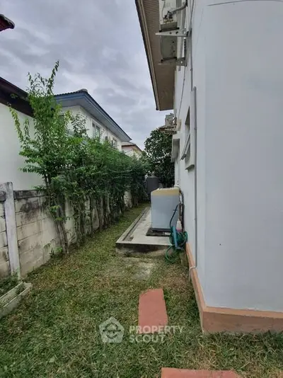 Side view of a house with garden and air conditioning units