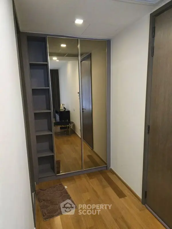 Modern hallway with mirrored closet doors and wooden flooring in a stylish apartment.