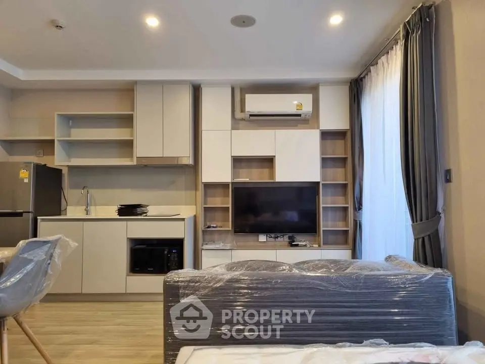 Modern living room with sleek kitchen, air conditioning, and stylish furniture in a cozy apartment.