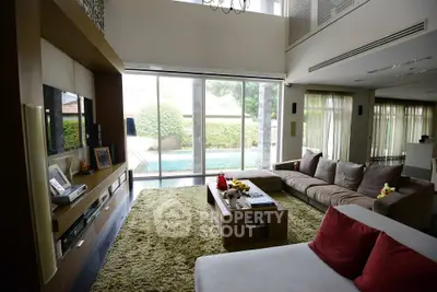 Luxurious living room with pool view, plush seating, and modern entertainment center.
