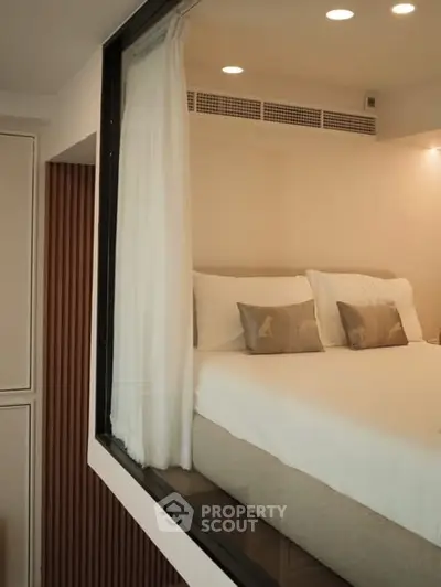 Modern bedroom with cozy bedding and ambient lighting, featuring a unique glass partition for a spacious feel.