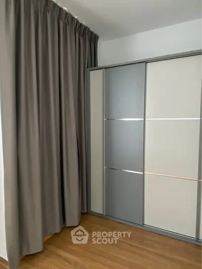 Modern bedroom with sleek sliding wardrobe and elegant floor-to-ceiling curtains.