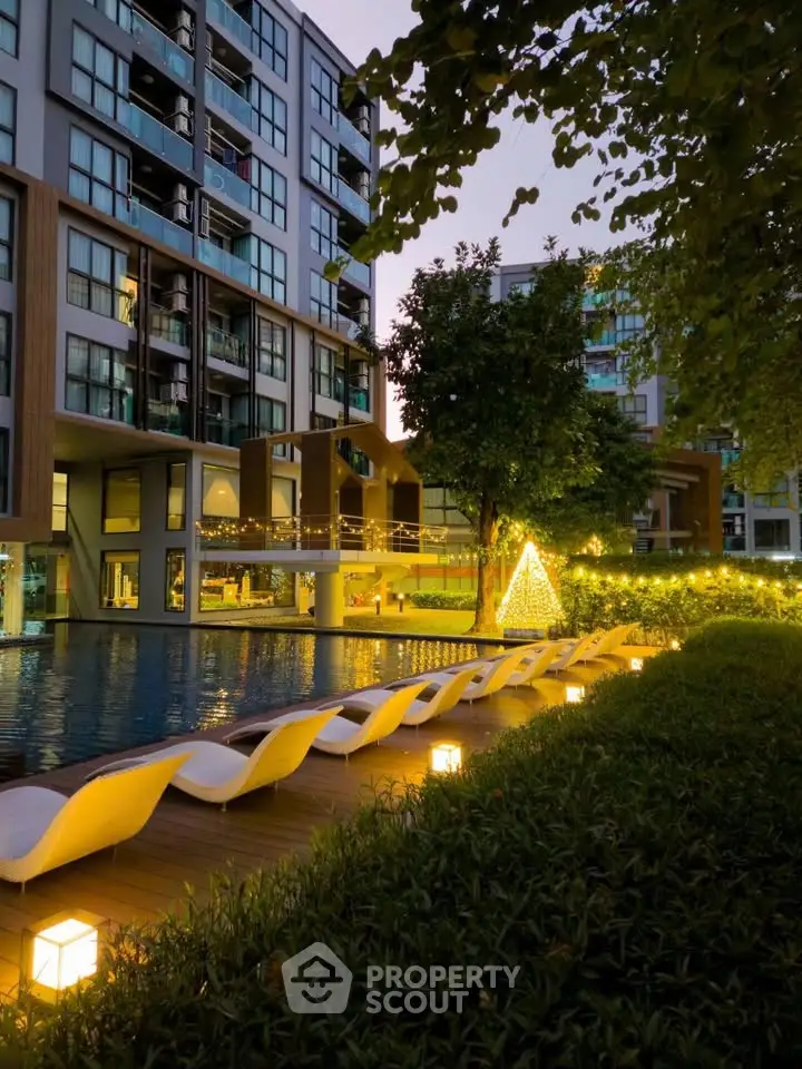 Luxurious apartment complex with illuminated poolside and modern architecture at dusk.