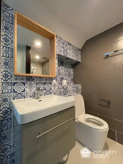 Charming bathroom with ornate blue and white tile work, modern fixtures, and sleek design, perfect for a contemporary home.