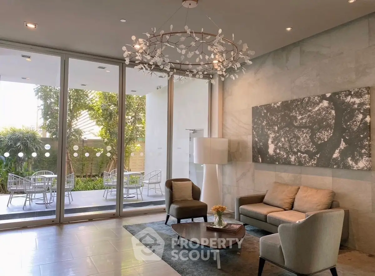 Elegant living room with modern decor and garden view, featuring stylish furniture and unique chandelier.