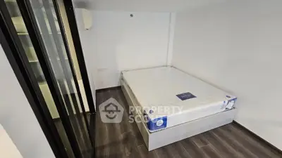 Modern bedroom with sleek flooring and a new mattress in a minimalist setting.