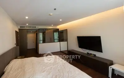 Spacious modern bedroom with wall-mounted TV and cozy lighting