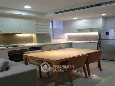 Modern kitchen with sleek cabinetry and dining area in contemporary apartment.