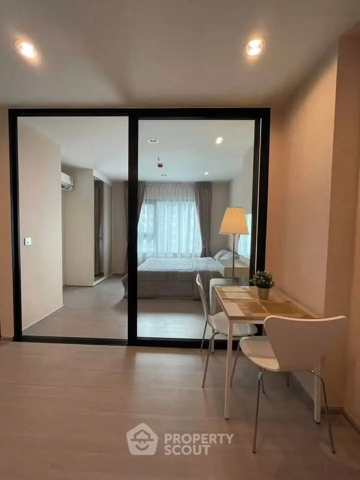 Modern apartment interior with glass partition, cozy bedroom, and stylish dining area.