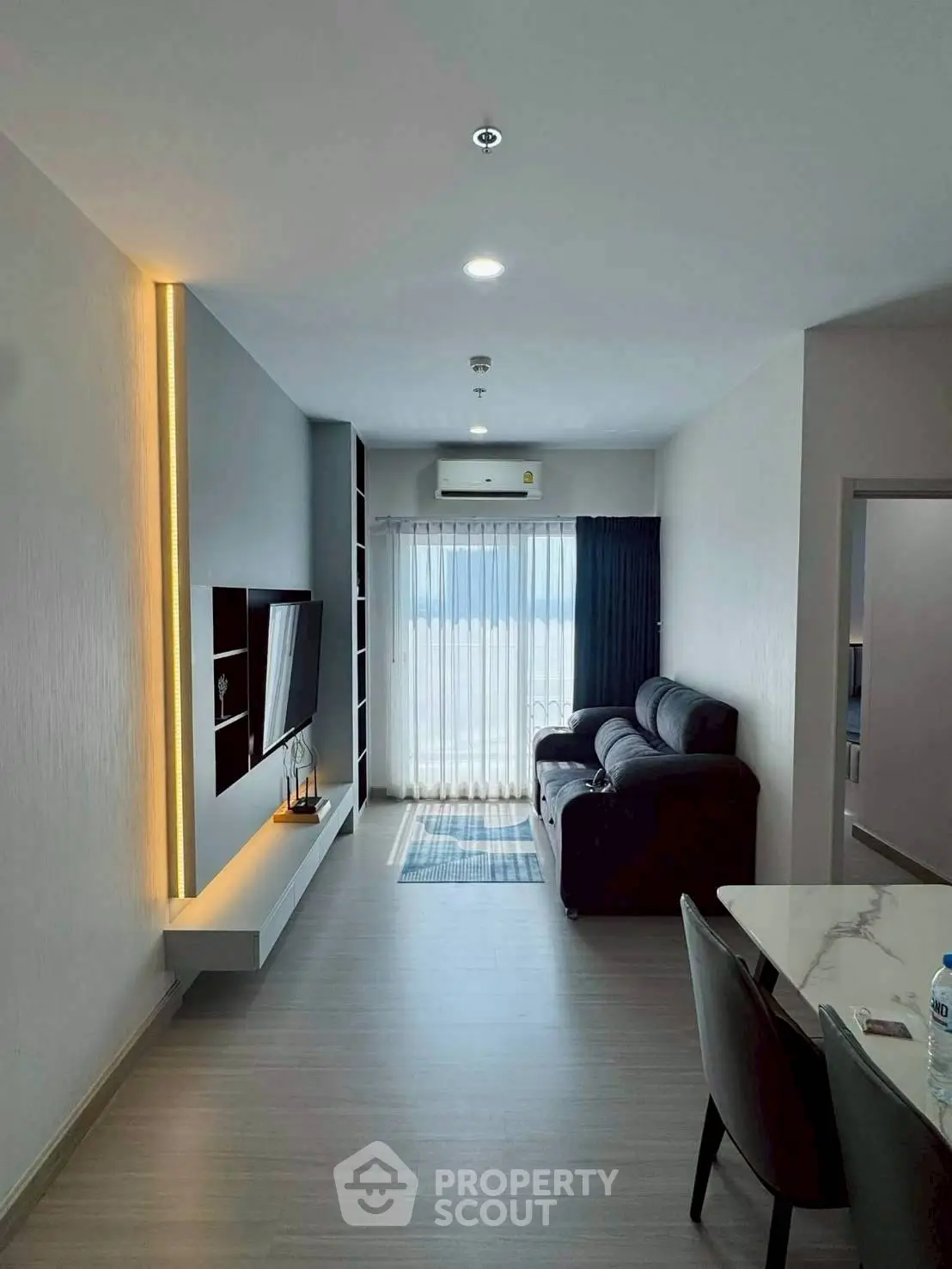 Modern living room with sleek design, featuring a cozy sofa, wall-mounted TV, and elegant lighting.