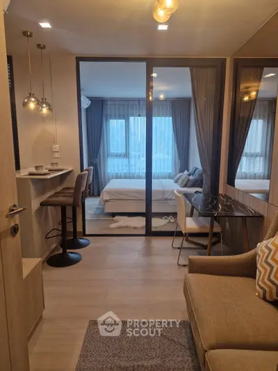 Modern studio apartment with open layout and stylish furnishings, featuring a cozy living area and elegant lighting.