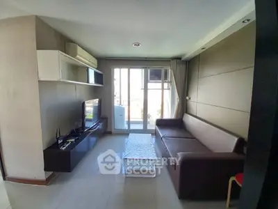 Modern living room with sleek furniture and natural light streaming in from the balcony, perfect for urban living.