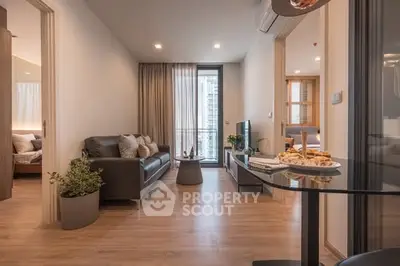 Modern living room with cozy seating and elegant decor, featuring a view of the bedroom and balcony.