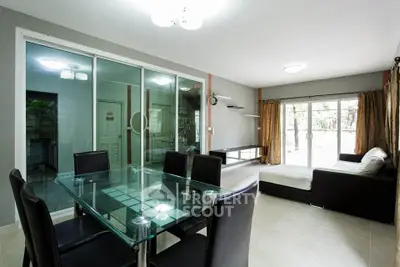Spacious modern living room with glass dining table and sliding doors to garden view.