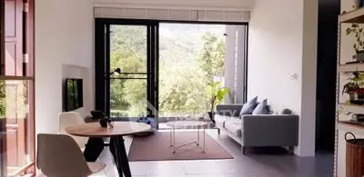Modern living room with large windows offering scenic views, stylish furniture, and natural light.