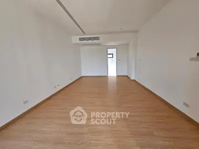 Spacious empty room with wooden flooring and modern air conditioning, perfect for customization.