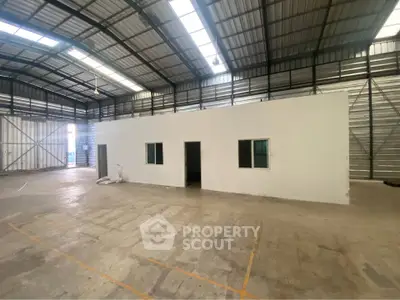 Spacious industrial warehouse interior with high ceilings and office space.