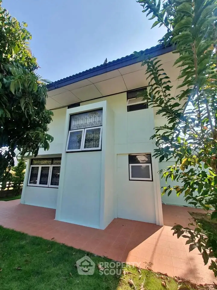 Modern two-story house with tiled patio and lush greenery