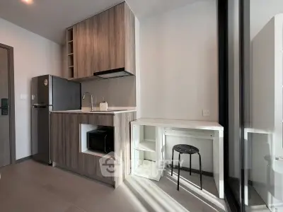 Modern kitchen with sleek cabinetry, stainless steel fridge, and compact dining area in a stylish apartment.