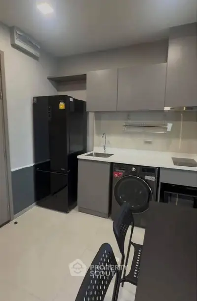 Modern kitchen with sleek appliances and minimalist design, featuring a washing machine and fridge.