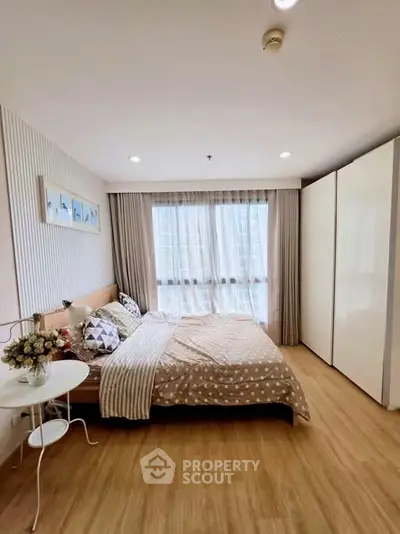 Cozy bedroom with large window and modern decor in a stylish apartment.