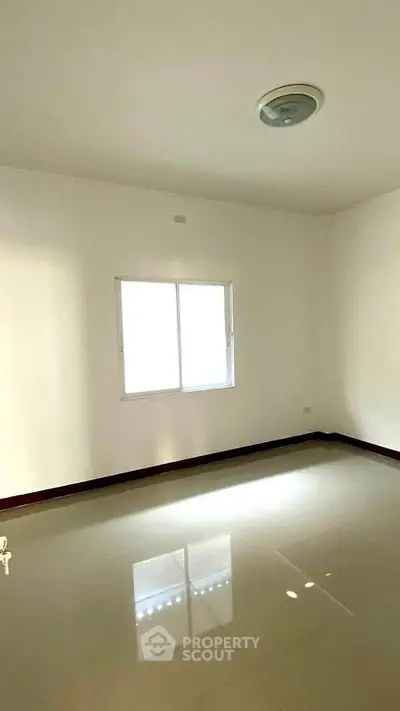 Spacious empty room with glossy tiled floor and bright window lighting.