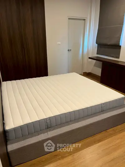 Spacious bedroom with modern design featuring a comfortable bed and stylish wooden accents.