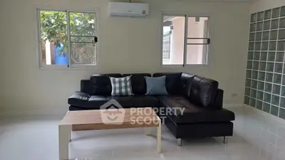 Modern living room with sleek black leather sofa and stylish wooden coffee table.