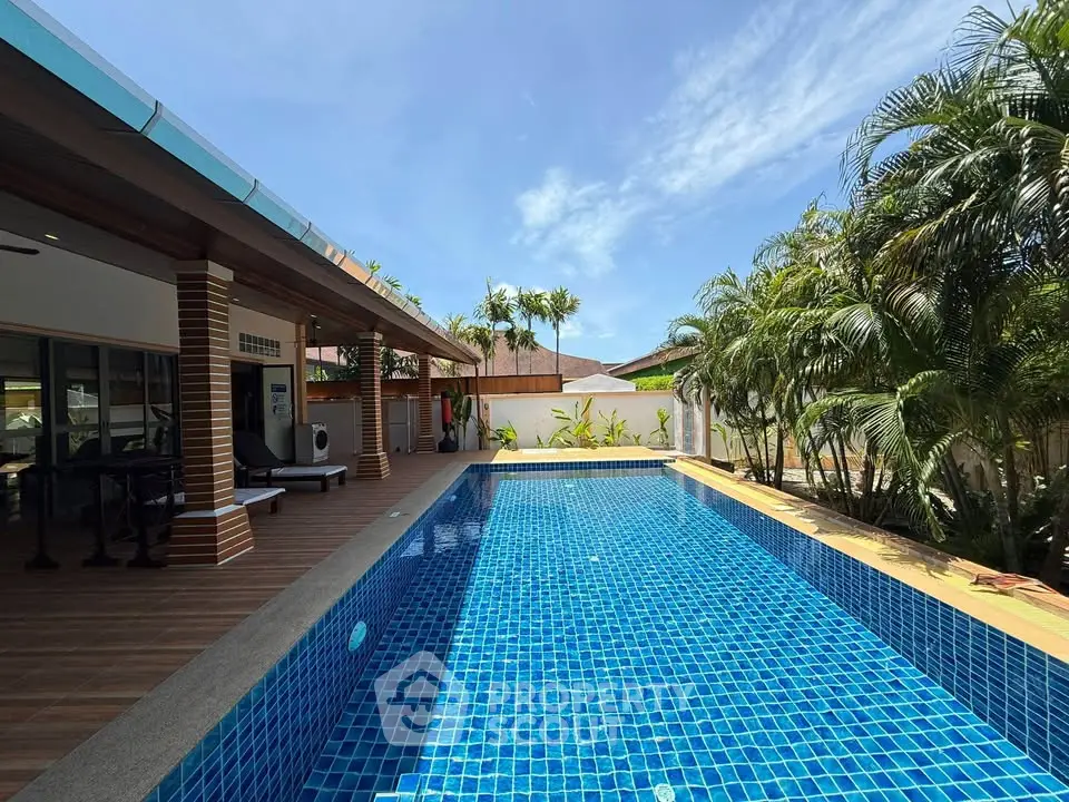 Luxurious outdoor pool area with tropical landscaping and spacious deck, perfect for relaxation and entertainment.