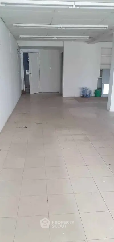 Spacious empty room with tiled flooring and white walls, ideal for customization.
