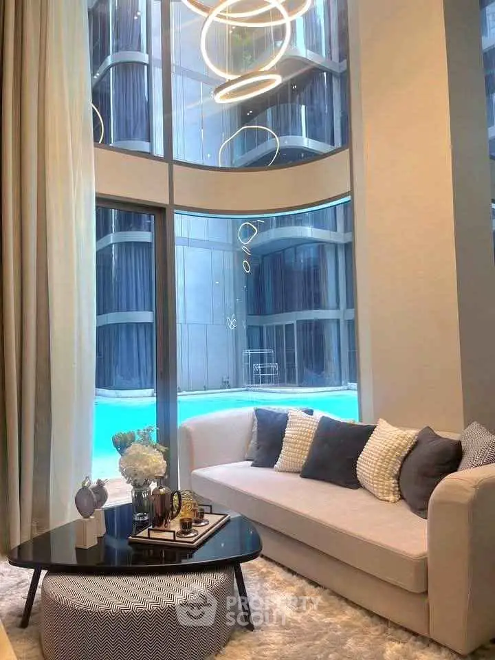 Luxurious living room with pool view and modern decor in high-rise building.