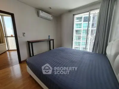 Modern bedroom with large window and city view, featuring air conditioning and sleek wooden flooring.