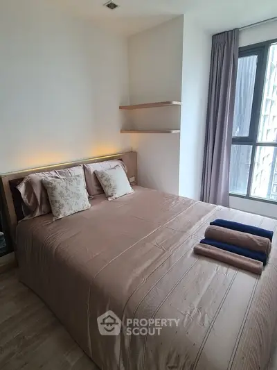 Cozy bedroom with modern design and large window offering natural light.