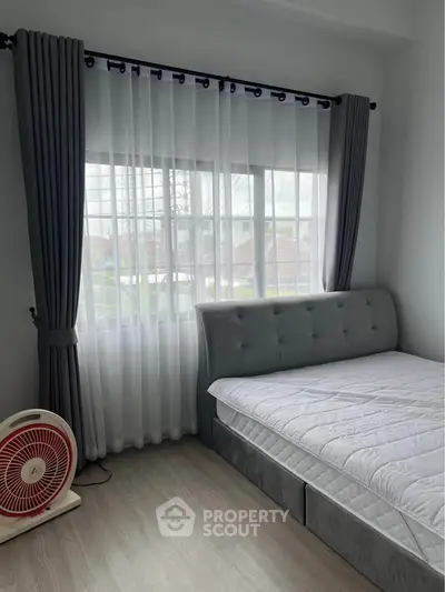 Bright bedroom with large window and modern decor, featuring a cozy bed and stylish curtains.