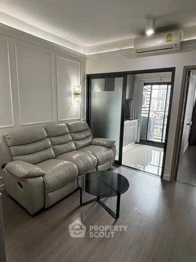 Modern living room with sleek design and city view, featuring a comfortable leather sofa and glass sliding doors.