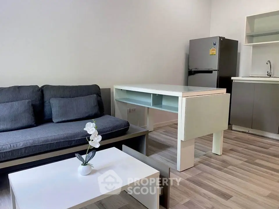 Modern living room with sleek furniture and open kitchen layout, featuring a cozy sofa and stylish decor.