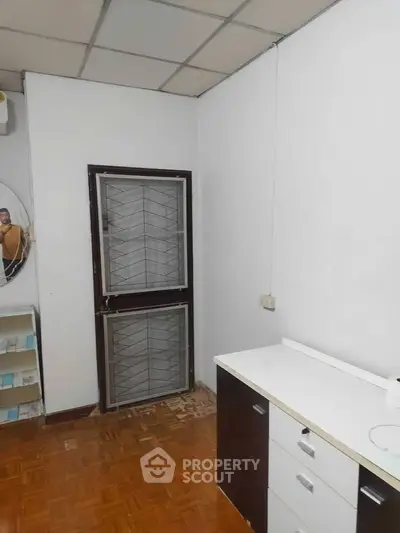 Compact study room with parquet flooring and built-in storage cabinets.
