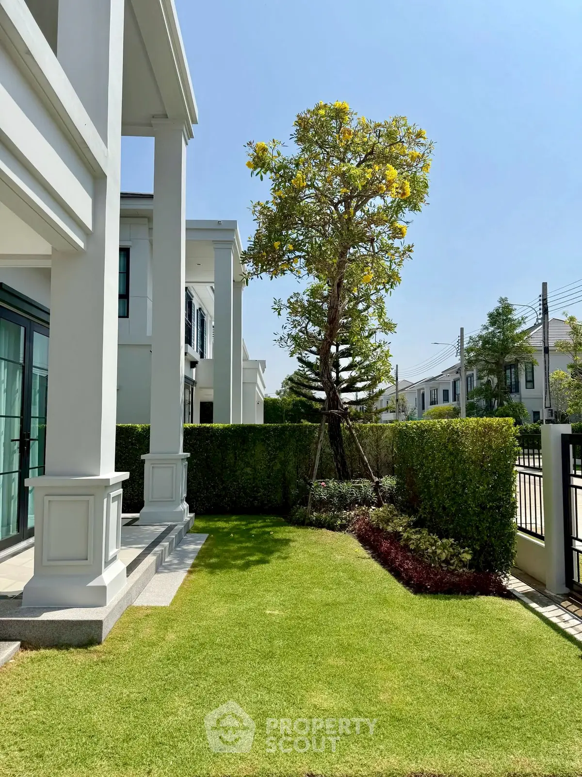 Elegant modern house exterior with lush garden and manicured lawn, showcasing luxury living in a serene neighborhood.