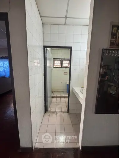 Spacious bathroom with tiled walls and natural light, ideal for renovation.