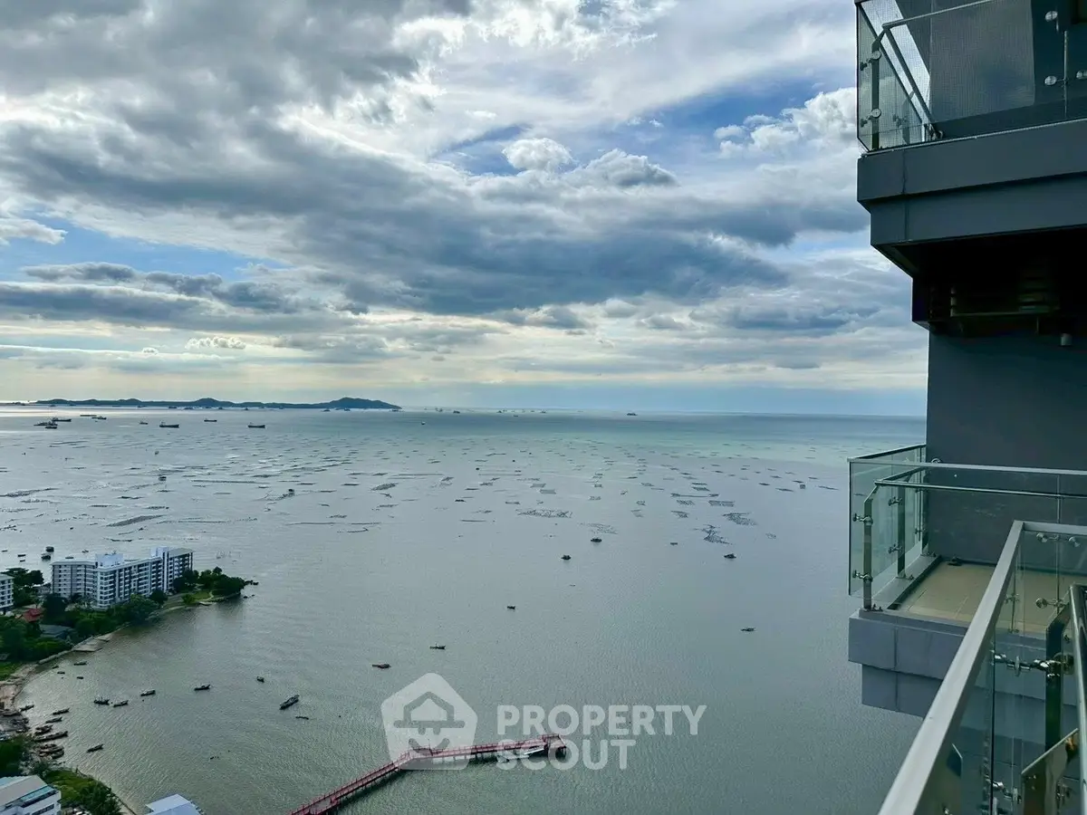 Stunning ocean view from high-rise balcony with glass railing, perfect for relaxation.