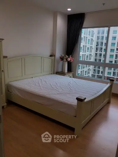 Cozy bedroom with large window offering city view and natural light.